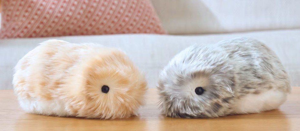 Il robot Casio Moflin, simile a una palla di pelo grigia, tenuto dolcemente tra le mani