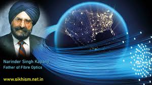 Narinder Singh Kapany nel suo laboratorio negli anni '50 tiene in mano fasci di fibre ottiche illuminate mentre dimostra la trasmissione della luce curva